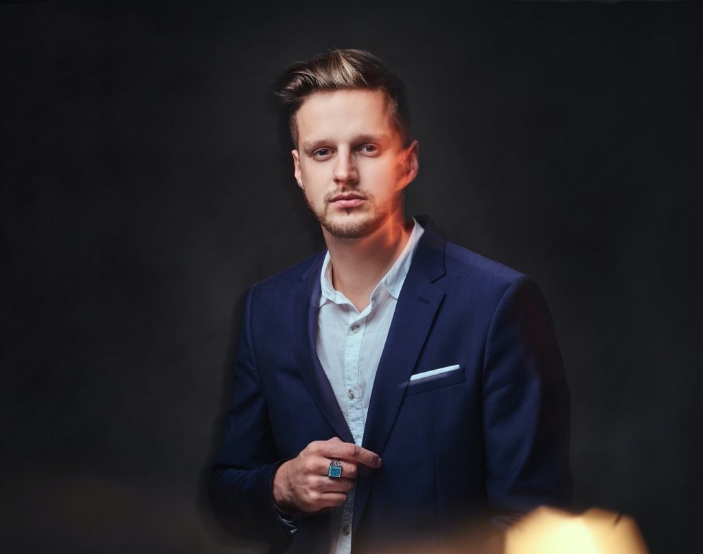 A man dressed in a suit over dark grey background.