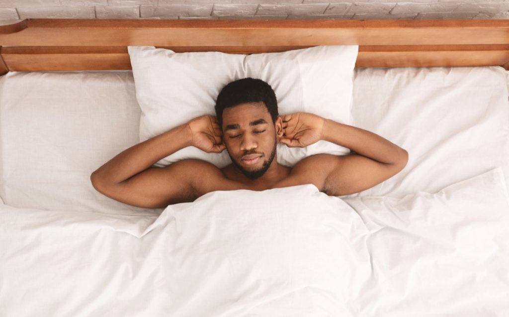 Relaxed african american man taking a nap relaxing in bed.