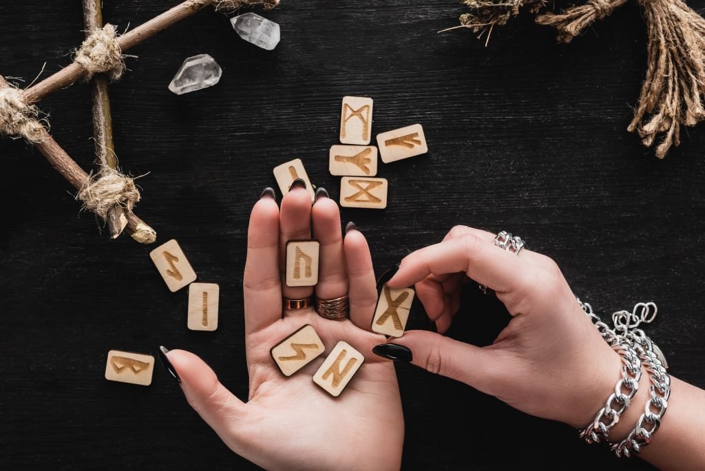 Top View of Woman Holding Runes in Hands Near Crystals on Black